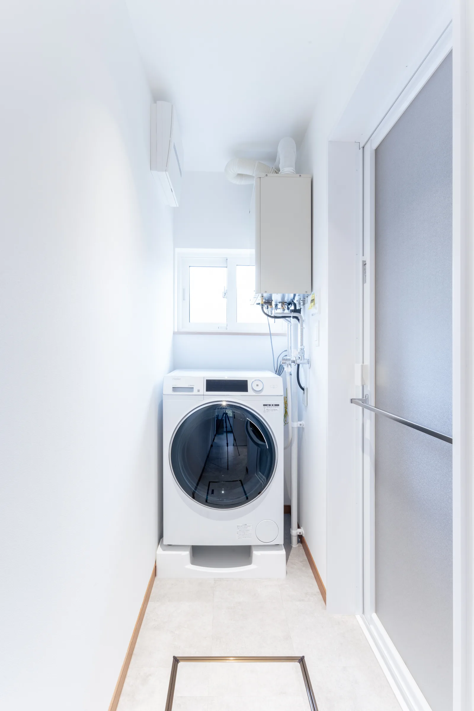 改修後のランドリー。白い壁と洗濯機